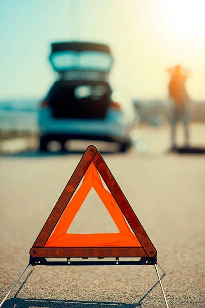 Triangolo di emergenza con un’auto ferma sullo sfondo